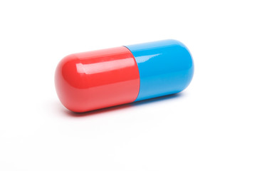 Big shiny red and blue capsule sitting with shadow on white background