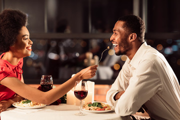 Joyful Couple Feeding Each Other During Romantic Date In Restaurant