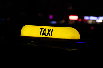 Taxi sign. Yellow taxi flasher by car at night. Luminous recognition signal. Taxi in the parking lot