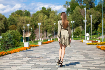 Young beautiful woman in green dress walking on the summer street