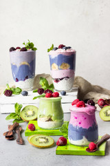 Colorful layered smoothie made of different berries, matcha tee and chia pudding in glasses. Clean eating, vegan, vegetarian, weight loss, healthy, diet food concept.
