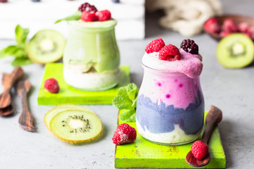 Colorful layered smoothie made of different berries, matcha tee and chia pudding in glasses. Clean eating, vegan, vegetarian, weight loss, healthy, diet food concept.