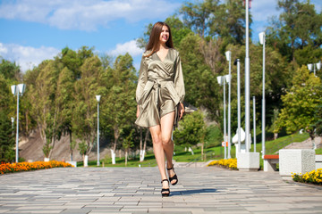 Fototapeta premium Young beautiful woman in green dress walking on the summer street