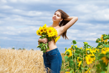 Sexy girl with a bouquet of sunflowers posing on a field background