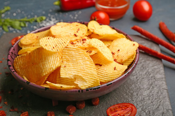 Plate with tasty potato chips on table