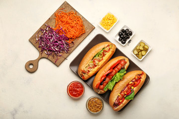 Composition with tasty hot dogs on light background