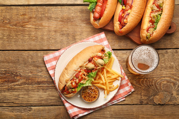 Tasty hot dogs with french fries and beer on wooden background