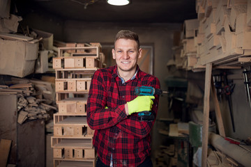 Carpenter looking at camera and holding drill in his workshop