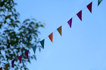 Fototapeta premium Colorful flags hung outdoor in a park. Selective focus.