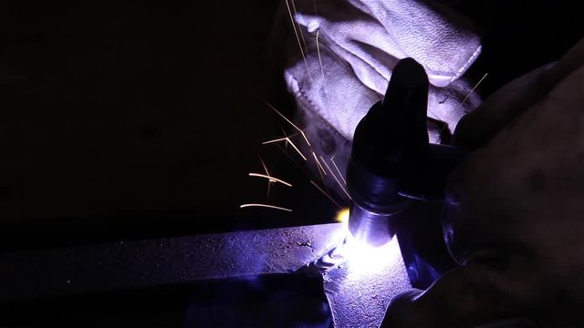 worker welding steel with mig welding torch machine