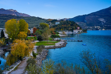 Fototapeta premium Beautiful and colorful autumn in Riva del Garda,Panorama of the gorgeous Garda lake surrounded by mountains in the autumn time
