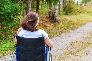 Young happy handicap woman in wheelchair on road in hospital park enjoying freedom. Paralyzed girl...
