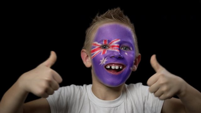 Happy boy rejoices victory of his favorite team of Australia. A child with a face painted in national colors. Portrait of a happy young fan. Joyful emotions and gestures. Victory. Triumph.
