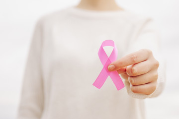 Stock photo of a woman with a pink ribbon, cancer symbol, in her hand