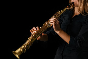 Naklejka premium soprano saxophone in hands on a black background