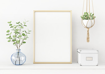 Interior poster mockup with vertical gold metal frame on the table with plants in blue vase and hanging macrame pot on empty white wall background. A4, A3 size format. 3D rendering, illustration.