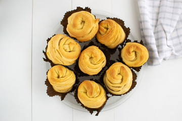 A lot of cruffins in brown paper forms on a white background