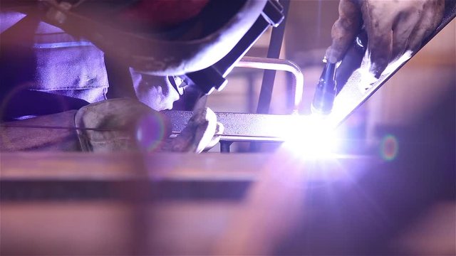 worker welding steel with mig welding torch machine