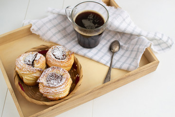 Cruffins with nut paste filling with a cup of espresso on a wooden tray.