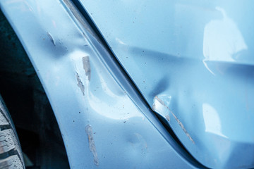 A large dent and cracked on the side wing of a blue car after an accident. Accident, car repair, insurance