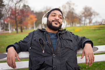 Man using headphones and tablet pc while sitting on the bench.