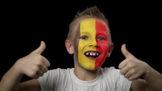 Happy boy rejoices victory of his favorite team of Belgium. A child with a face painted in national colors. Portrait of a happy young fan. Joyful emotions and gestures. Victory. Triumph.