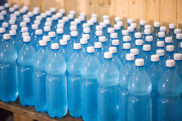 Production of mineral water on a small family business. The water is poured into plastic 1.5 liter PETE bottles. Many unlabeled bottles, swirled with white lids, stand on the table.
