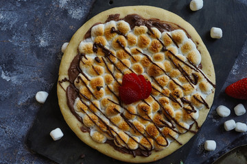 Homemade s'mores desser tpizzatopped with toasted marshmallows and chocolate drizzle