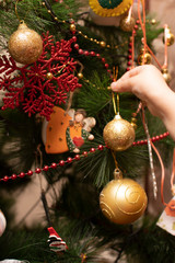 Child's hand attaches decoration bubble to a Christmas tree