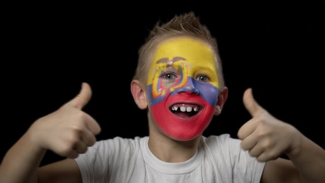 Happy boy rejoices victory of his favorite team of Ecuador. A child with a face painted in national colors. Portrait of a happy young fan. Joyful emotions and gestures. Victory. Triumph.