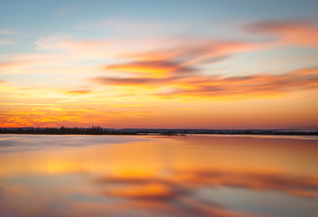 Early morning shot of a sunrise with wispy clouds and reflection on the water at Paynes Prairie