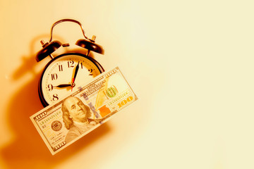 Time is money concept. Alarmclock with hundred US Dollars.