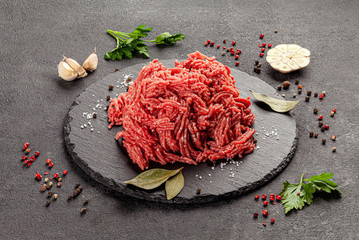 Raw meat products. Veal or mixed homemade minced meat with spices on a black background. board...