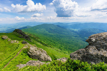 Fototapeta na wymiar mountain landscape in summer. view from the top of carpathian watershed ridge in to the distance. boulders on the green grassy slopes. sunny weather with clouds on the blue sky