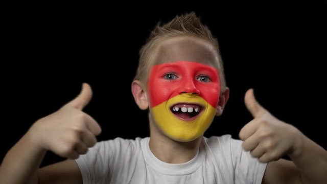 Happy boy rejoices victory of his favorite team of Germany. A child with a face painted in national colors. Portrait of a happy young fan. Joyful emotions and gestures. Victory. Triumph.