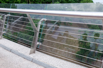 construction of a glass bridge with steel fixtures with a railing and a granite curb, city scape on background nobody.