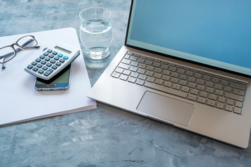 business workspace with accounting  equipment like laptop, calculator, paper and water glass on a...