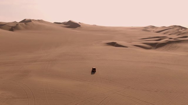 Dune buggy. Sandy desert oasis lake. DRONE. Adventure Dune Buggy. Speed. Tourism shot in Huacachina, Peru. Epic, Fast. Water in middle of hot sand desert. Romantic, holiday, honeymoon, scenic shot.