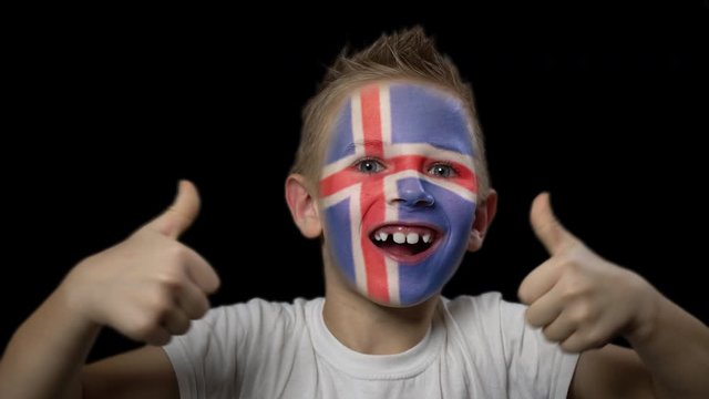 Happy boy rejoices victory of his favorite team of Iceland. A child with a face painted in national colors. Portrait of a happy young fan. Joyful emotions and gestures. Victory. Triumph.