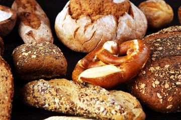 Assortment of baked bread and bread rolls and cutted bread on table background