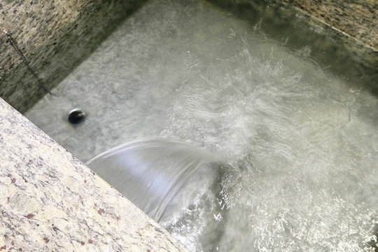 Closeup of jet of water in stone bathtub                                                                                                                                                                