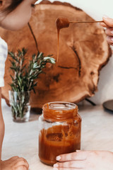 Caramel in glass jar. Caramel cream on spoon.
