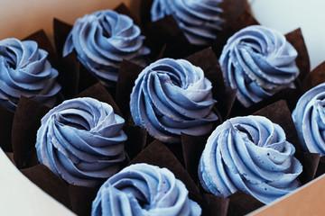 Decoration with blue purple cream muffins. Cooking chocolate cream cupcakes. Confectioner cooks in kitchen.