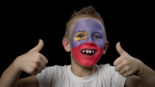 Happy boy rejoices victory of his favorite team of Liechtenstein. A child with a face painted in national colors. Portrait of a happy young fan. Joyful emotions and gestures. Victory. Triumph.