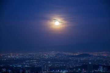 Naklejka premium Luna llena sobre la ciudad