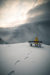 Man sitting on a wooden bench on Mountain Peak in Winter