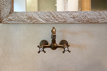 Close up antique bronze hot and cold basin faucet with wooden mirror frame