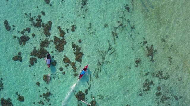 Aerial view or top view of long-tailed boat is float on the emerald sea. Calm andaman sea at Koh Lipe, Satun, Thailand. Rotation and tracking motion.