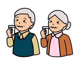 コップに入れた牛乳を飲んでしかめっ面をしている高齢者