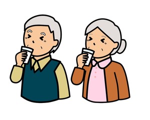 コップに入れた牛乳を飲んでしかめっ面をしている高齢者